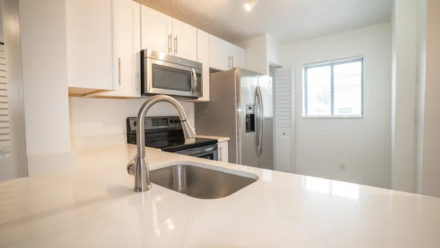 a kitchen with stainless steel appliances a sink a stove and a refrigerator with wooden floor