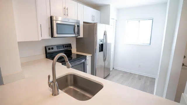 a kitchen with stainless steel appliances a refrigerator a sink a stove a microwave and cabinets