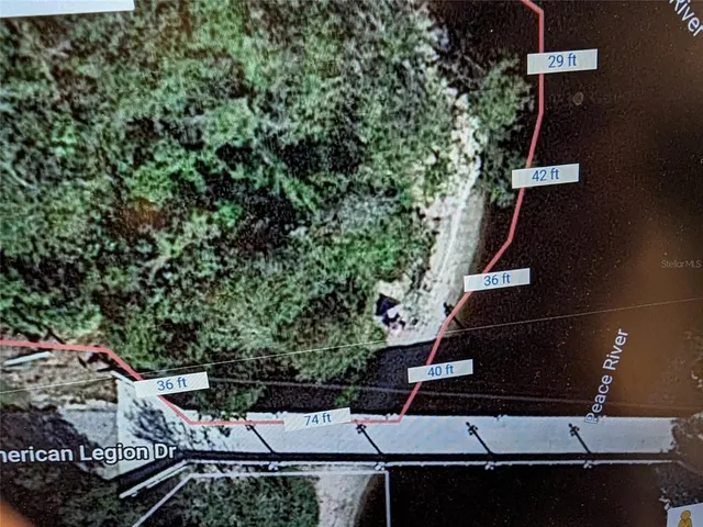 a view of a patio with table and chairs under an umbrella with large trees