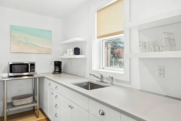 a kitchen with stainless steel appliances a sink a stove and white cabinets with wooden floor