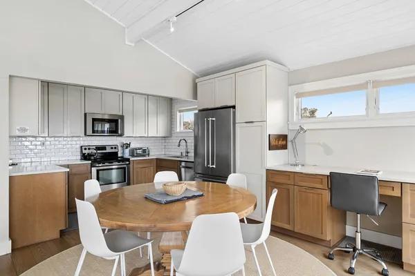 a kitchen with stainless steel appliances granite countertop a dining table chairs refrigerator and microwave