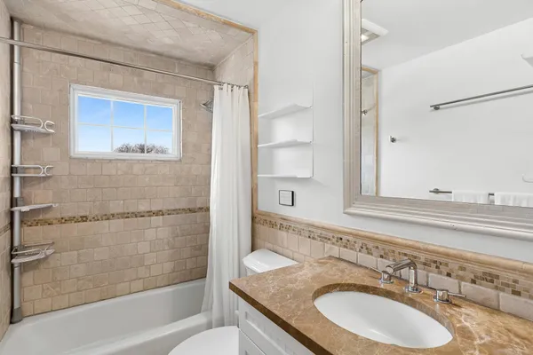 a bathroom with a granite countertop sink a mirror a bathtub and shower