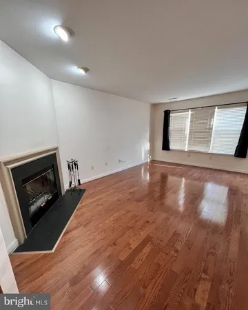 a view of an empty room with wooden floor and a fireplace