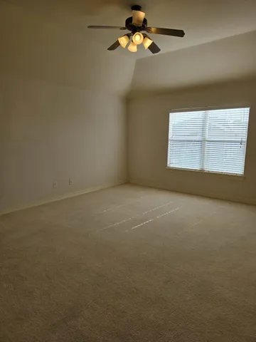 an empty room with a window and a ceiling fan