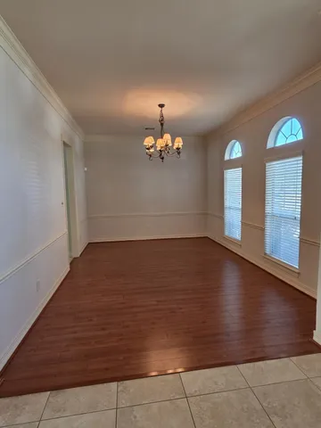 a view of wooden floor chandelier and windows in a room