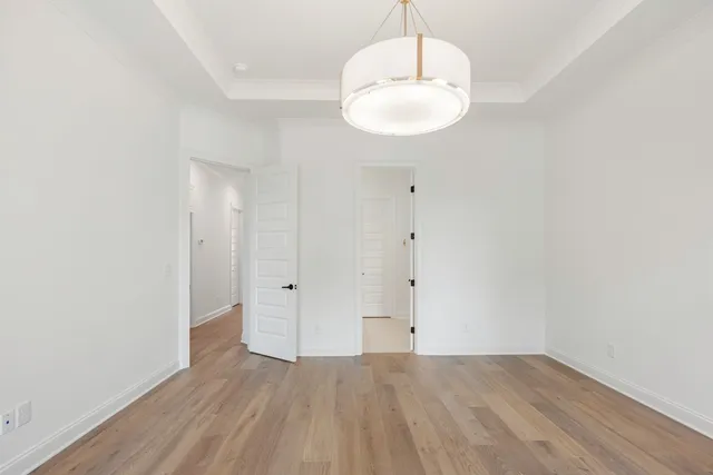 a view of an empty room with wooden floor and windows