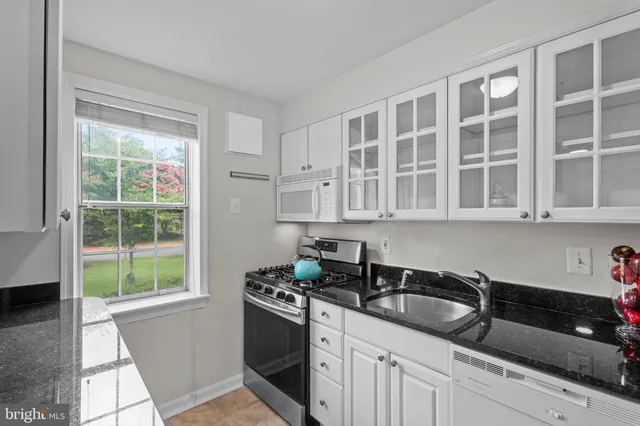 a kitchen with granite countertop a sink stove top oven and cabinets