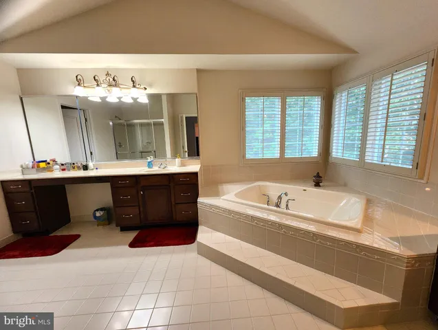 a spacious bathroom with a tub a double vanity sink a vanity a window and a mirror