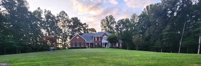 a view of a big house with a big yard and large trees