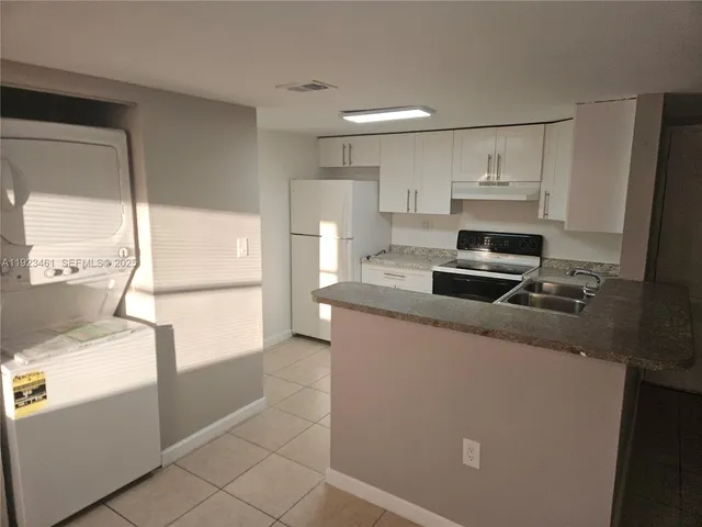 a kitchen with kitchen island white cabinets and refrigerator