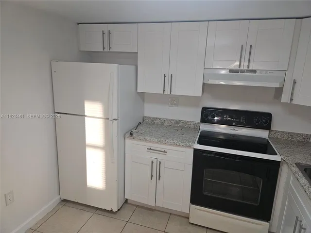 a kitchen with white cabinets and a stove with a sink