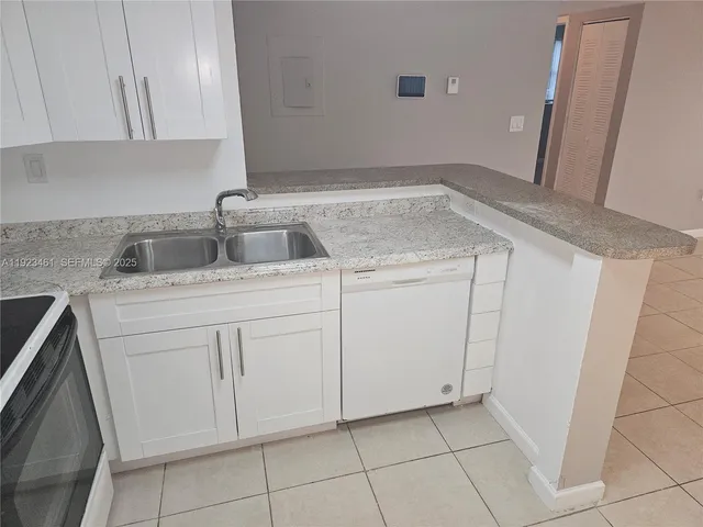 a kitchen with white cabinets washer and dryer