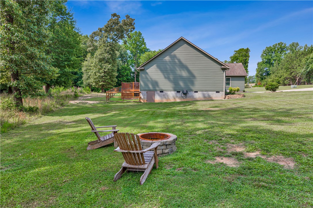 842 Conneross Road Townville, SC 29689 - Photo 31 of 34 A spacious lawn with a cozy fire pit and two Adirondack chairs, perfect for outdoor relaxation.