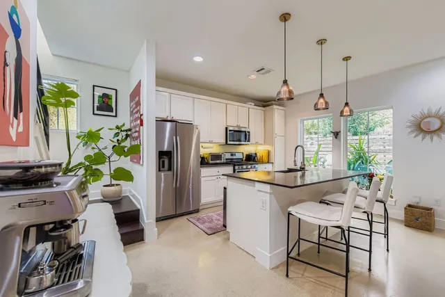 a kitchen with a refrigerator a stove a sink dishwasher a dining table and chairs with wooden floor