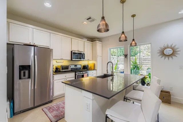 a kitchen with stainless steel appliances granite countertop a refrigerator a sink a stove a dining table and chairs