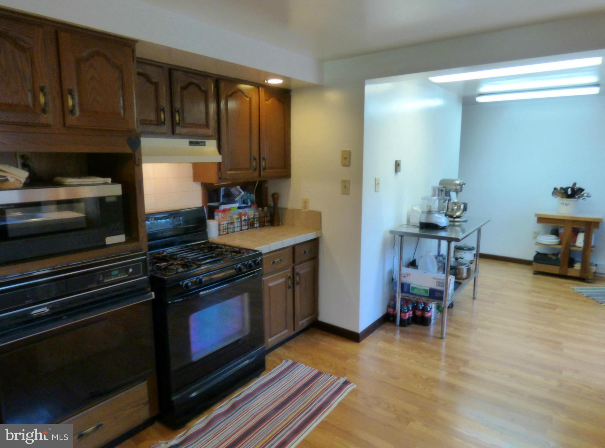 8409 Mapleville Road Mount Airy, MD 21771 - Photo 9 of 30 a kitchen with stainless steel appliances a stove a sink cabinets and a wooden floor