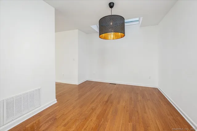 an empty room with wooden floor and fan
