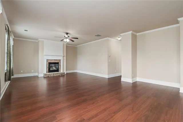 an empty room with wooden floor fireplace and windows