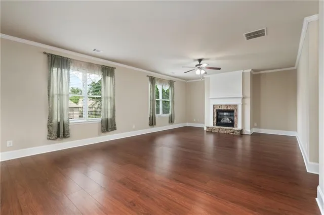 an empty room with wooden floor fireplace and windows