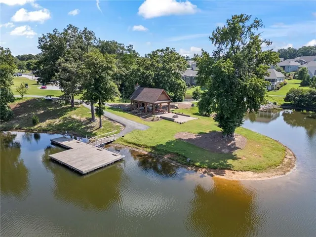 a view of a lake with lawn chairs and large trees