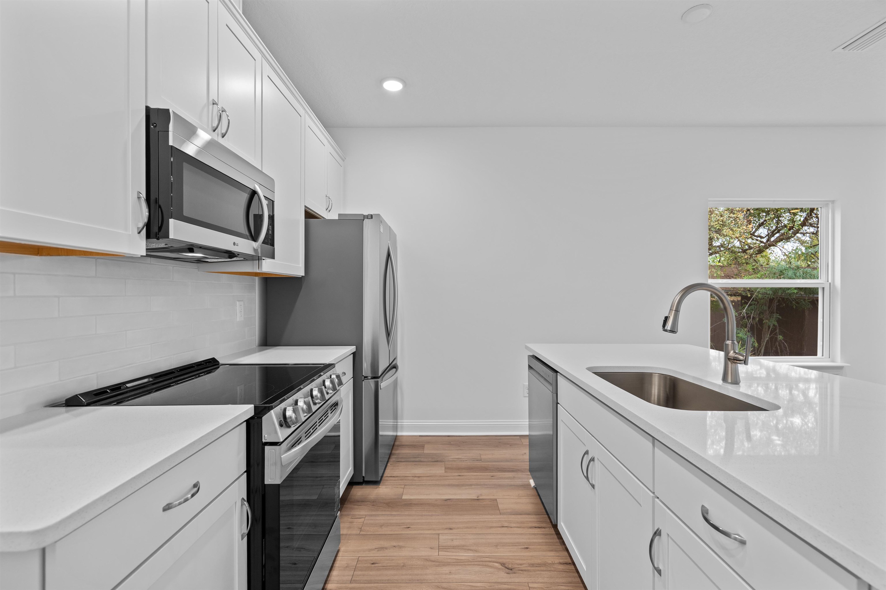 108 Aspen Road St. Augustine, FL 32086 - Photo 12 of 24 Kitchen with white cabinetry, stainless steel appliances, light stone countertops, light wood-style floors, and recessed lighting