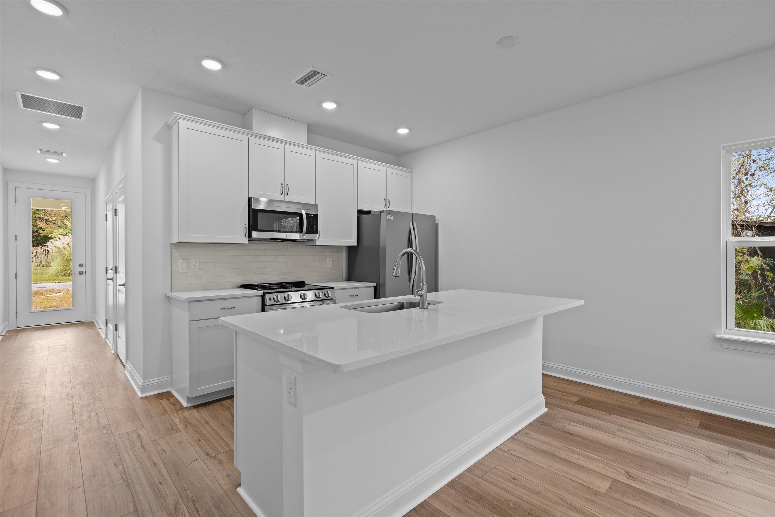 108 Aspen Road St. Augustine, FL 32086 - Photo 13 of 24 Kitchen featuring white cabinetry, an island with sink, stainless steel appliances, light wood-style flooring, and recessed lighting
