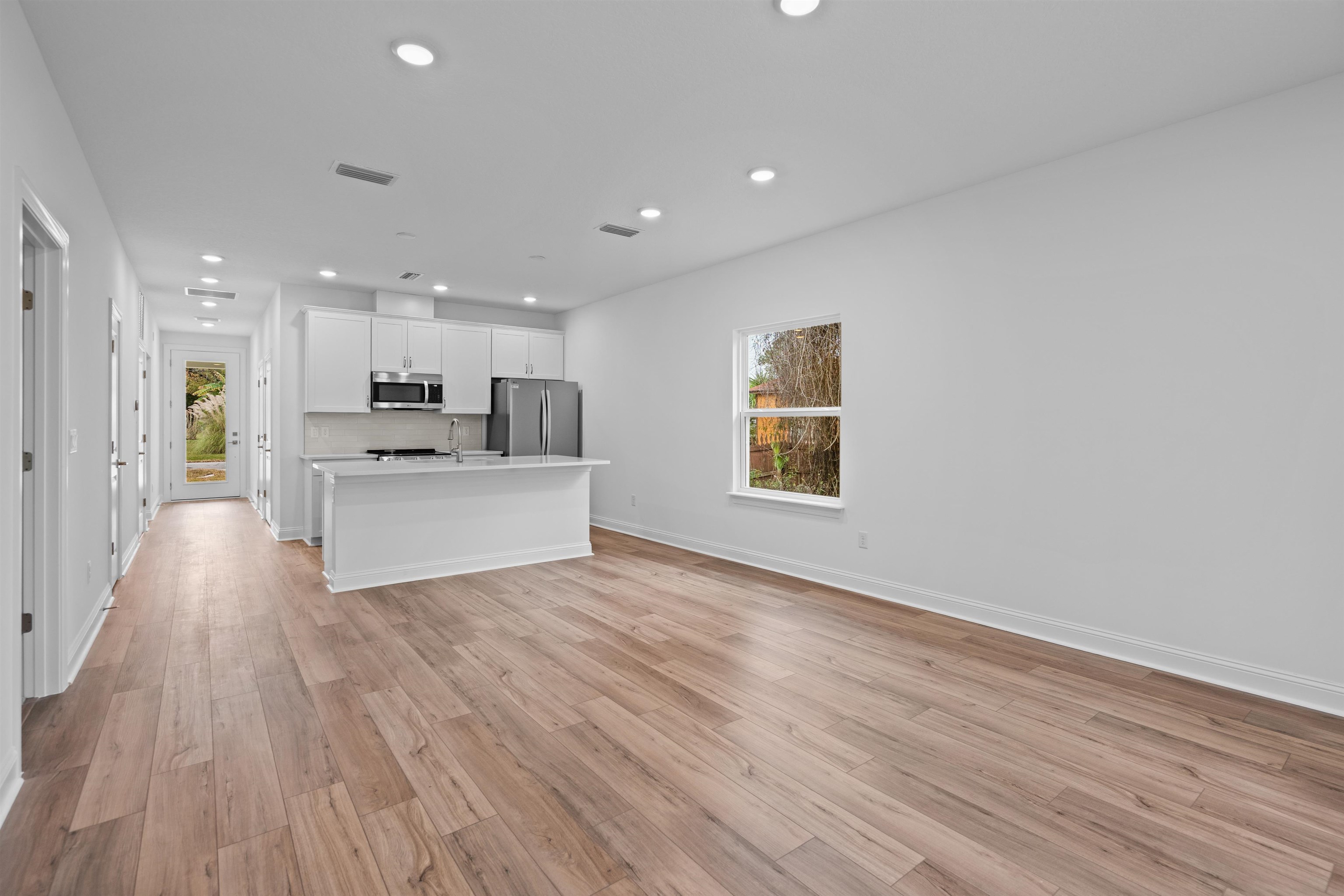 108 Aspen Road St. Augustine, FL 32086 - Photo 23 of 24 Kitchen with white cabinetry, an island with sink, open floor plan, light countertops, and stainless steel appliances