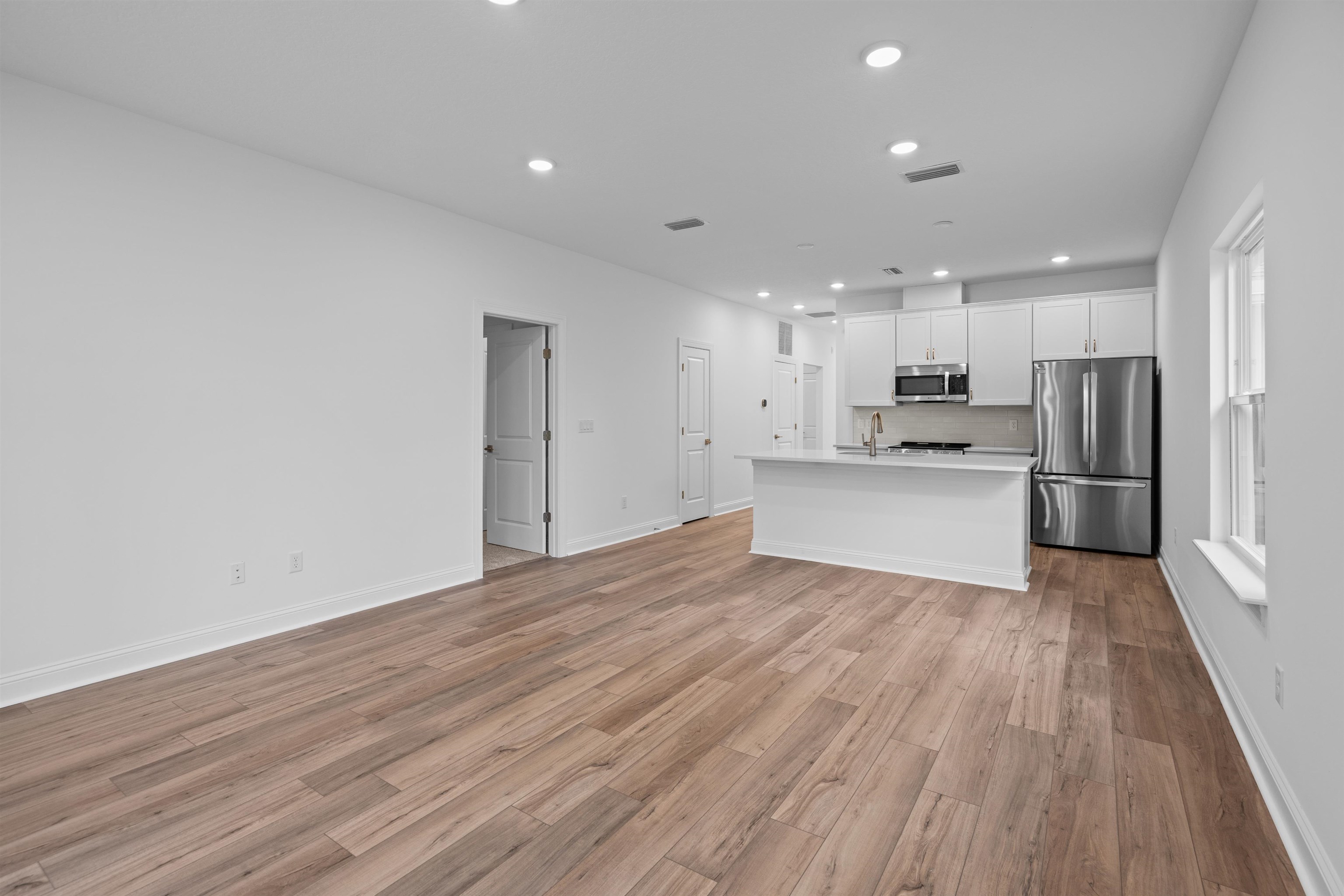 108 Aspen Road St. Augustine, FL 32086 - Photo 24 of 24 Kitchen with a center island with sink, open floor plan, stainless steel appliances, recessed lighting, and white cabinetry