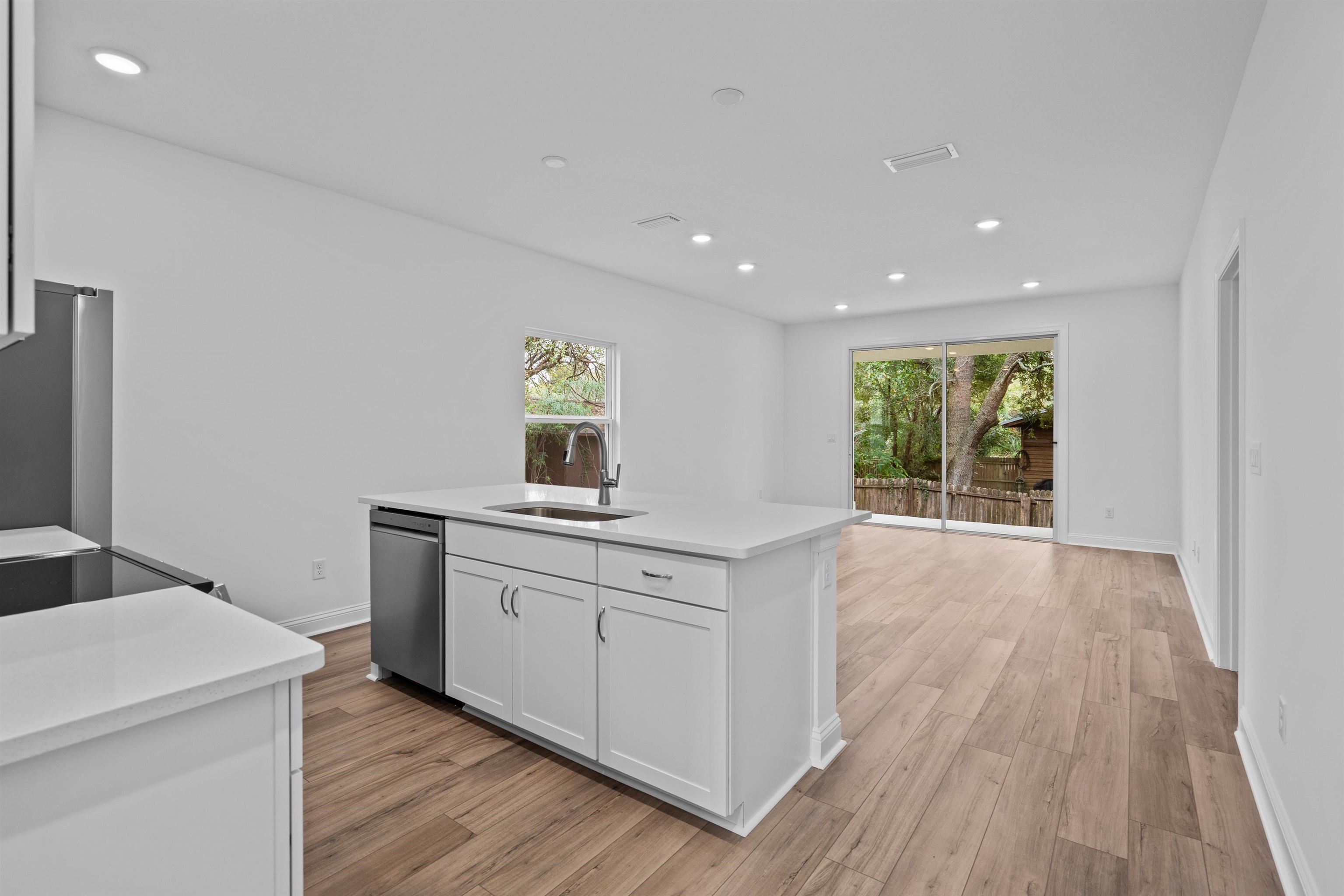 108 Aspen Road St. Augustine, FL 32086 - Photo 10 of 24 Kitchen featuring light wood-style flooring, white cabinets, recessed lighting, stainless steel appliances, and an island with sink