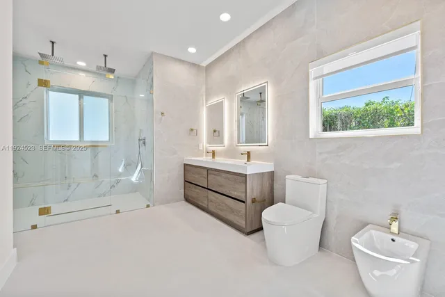 a bathroom with a double vanity sink a toilet and shower