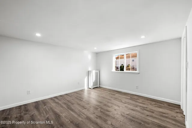 an empty room with wooden floor and window