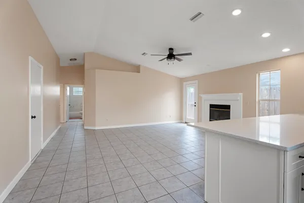 a view of an empty room with window and a kitchen