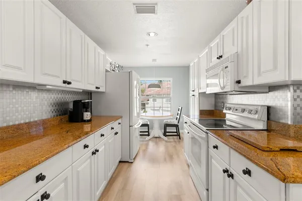 a kitchen with granite countertop a sink stove and cabinets
