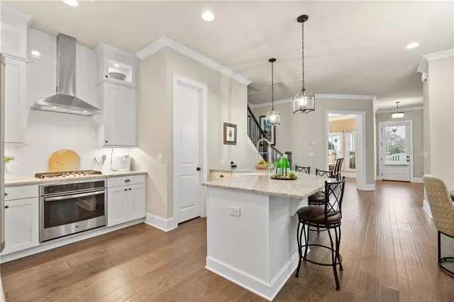 a kitchen with stainless steel appliances a stove a sink a center island a sink cabinets and wooden floor