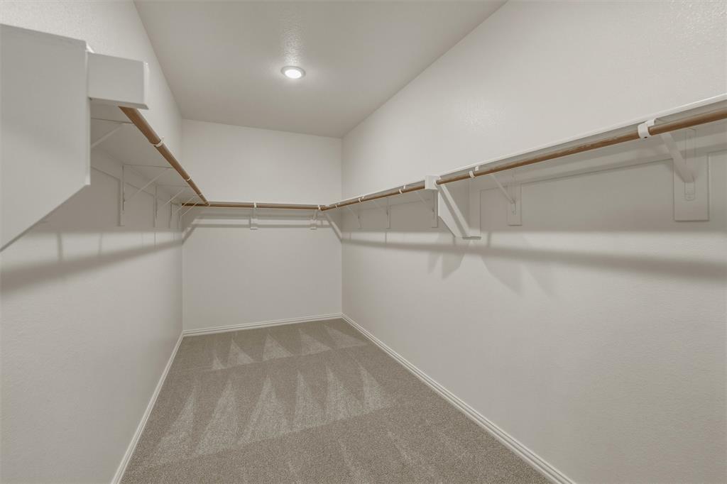 1325 Frio Drive Springtown, TX 76082 - Photo 13 of 24 Walk-in closet featuring light gray patterned carpet, white baseboards, and built-in white shelving with natural wood rods