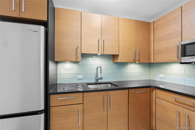 a kitchen with stainless steel appliances granite countertop a sink a refrigerator and a white cabinets