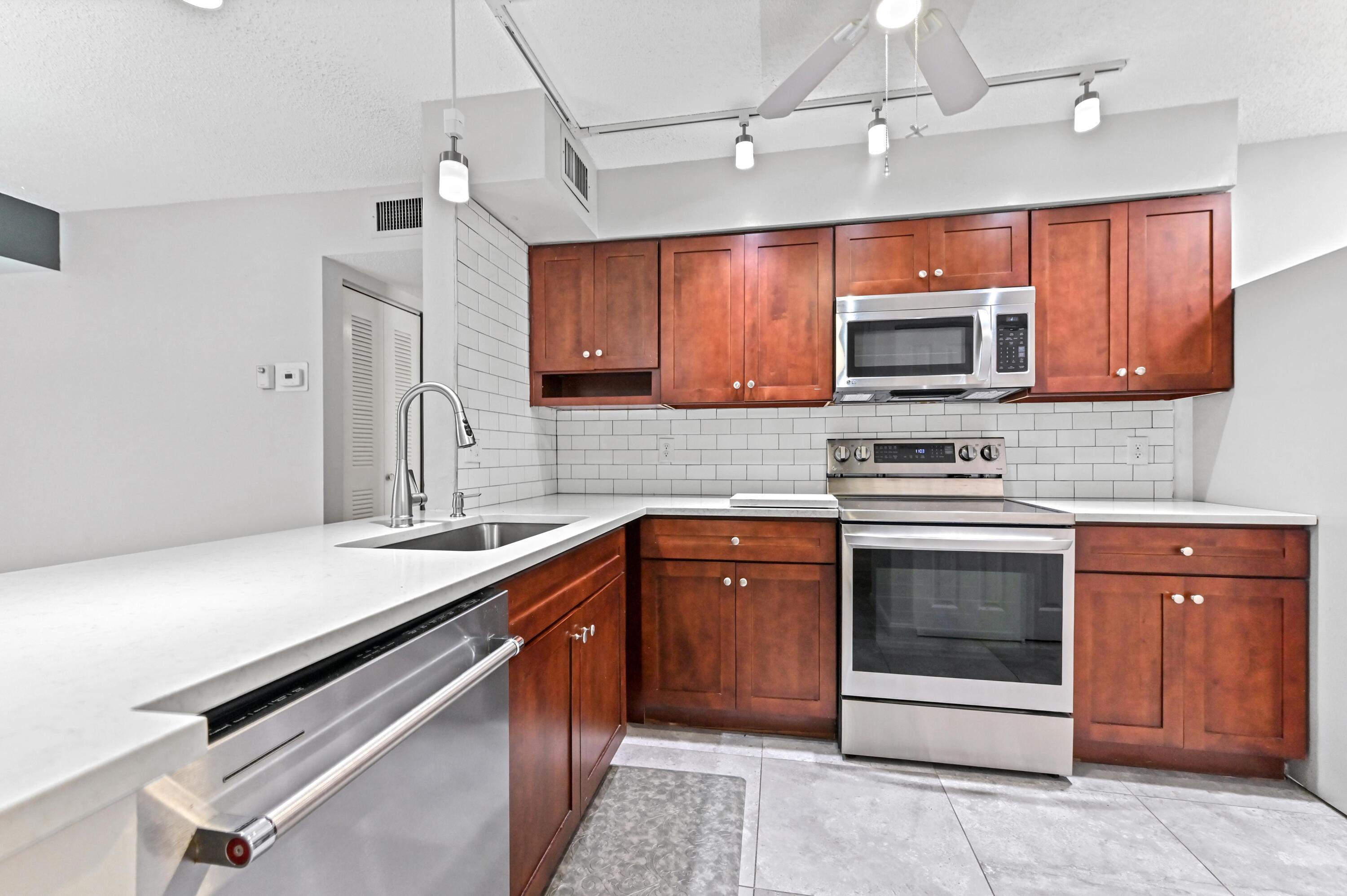 14895 Builtmore Way, Unit 107 Delray Beach, FL 33446 - Photo 12 of 40 a kitchen with stainless steel appliances granite countertop a sink and a stove top oven with granite countertops