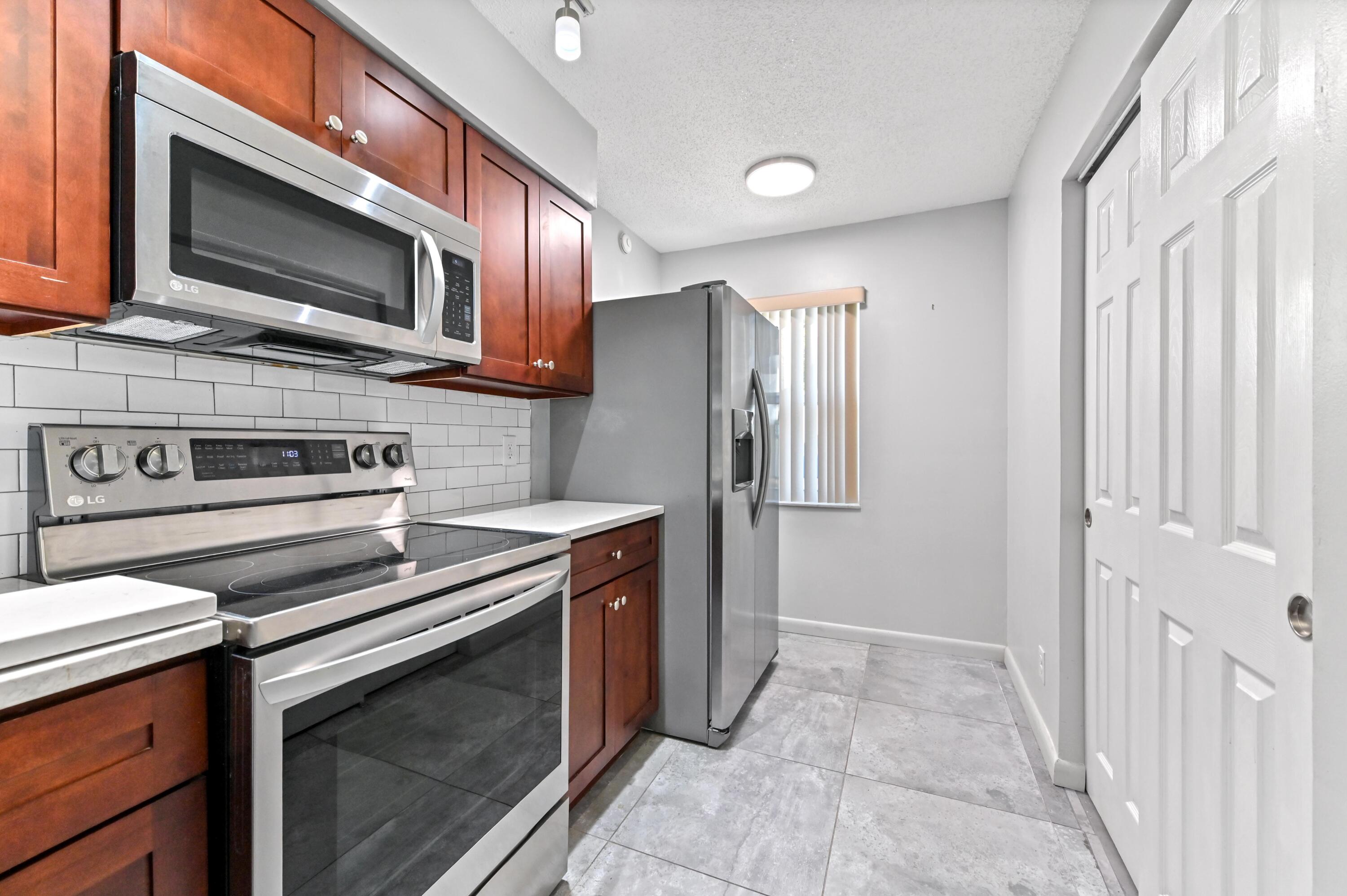 14895 Builtmore Way, Unit 107 Delray Beach, FL 33446 - Photo 13 of 40 a kitchen with stainless steel appliances granite countertop a stove microwave and refrigerator