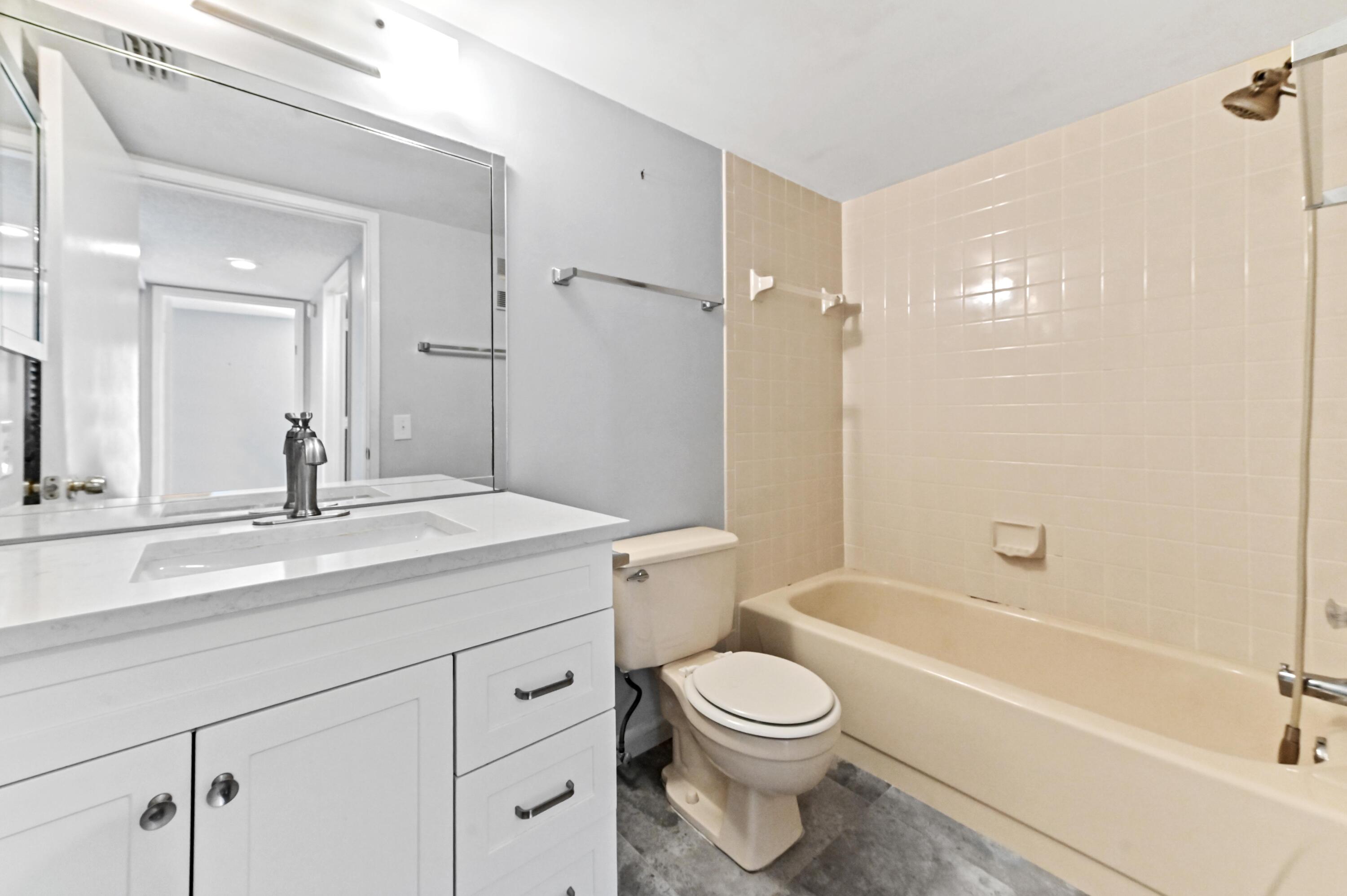 14895 Builtmore Way, Unit 107 Delray Beach, FL 33446 - Photo 18 of 40 a bathroom with a granite countertop sink a toilet and shower