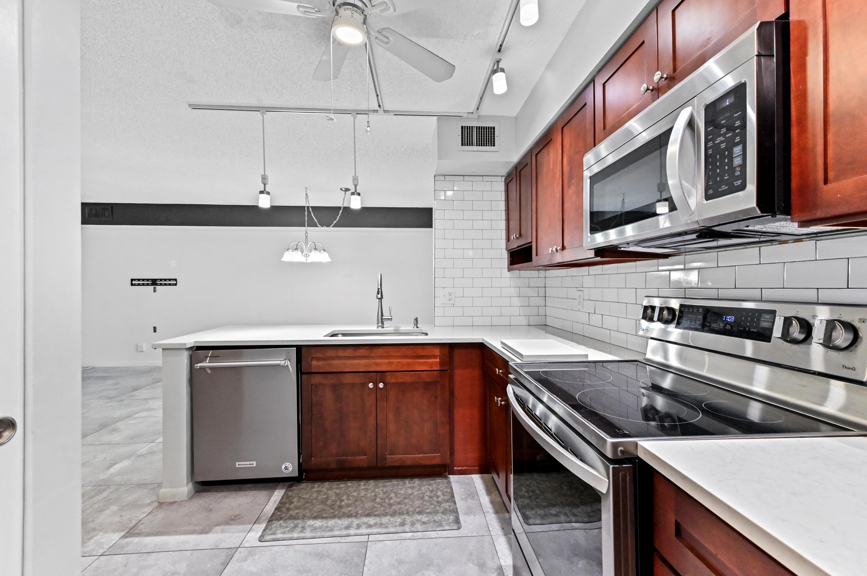 14895 Builtmore Way, Unit 107 Delray Beach, FL 33446 - Photo 6 of 40 a kitchen with stainless steel appliances granite countertop a sink and a stove