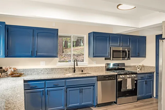 a kitchen with granite countertop stainless steel appliances a sink cabinets and a counter top space