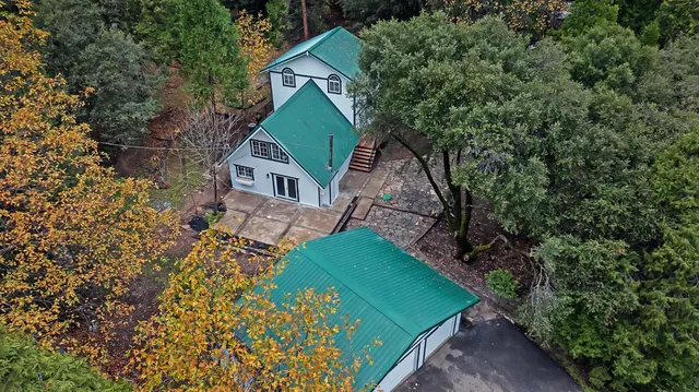 a view of a house with a yard and large trees