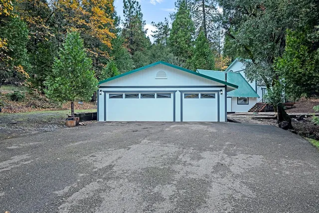 a view of a house with a yard and large trees