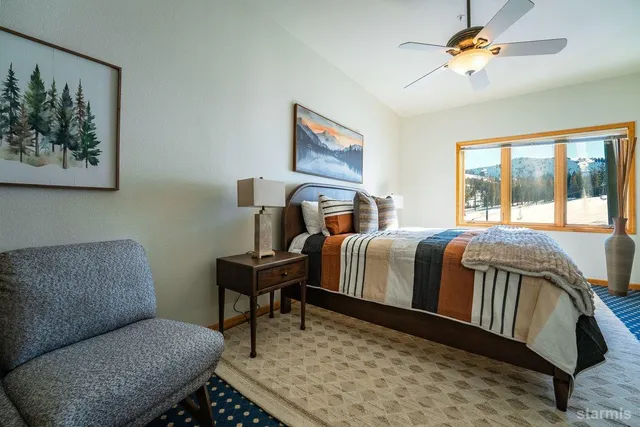 a bedroom with a bed dresser and a flat tv screen next to a window