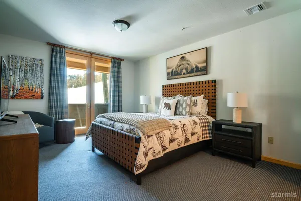 a bedroom with a bed dresser and a flat tv screen next to a window