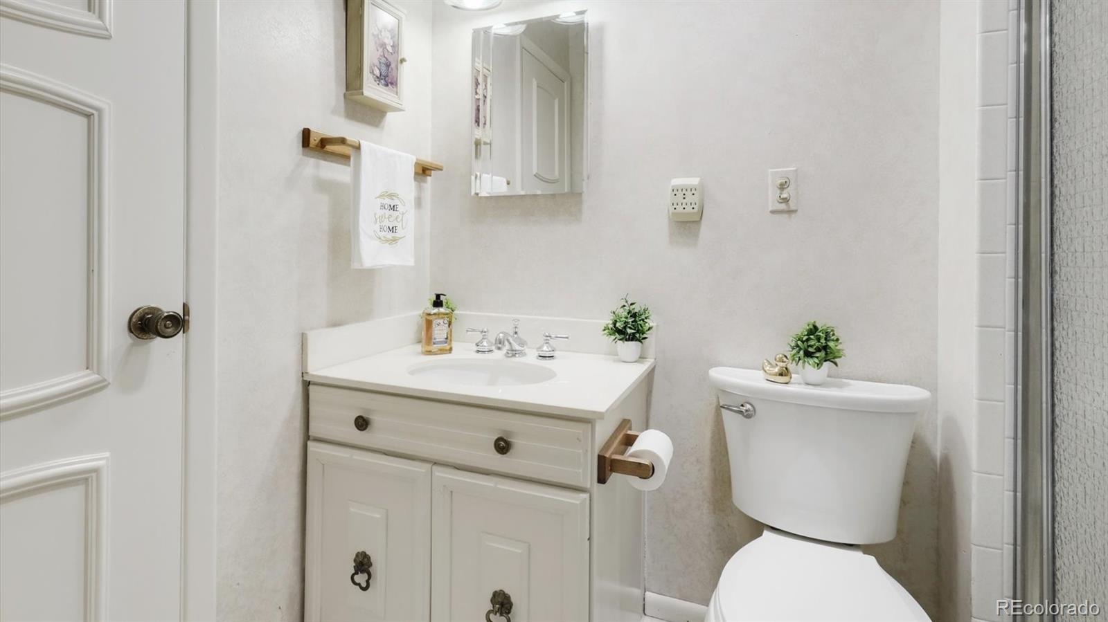 3292 South Oneida Way Denver, CO 80224 - Photo 15 of 44 a bathroom with a sink a toilet and a mirror