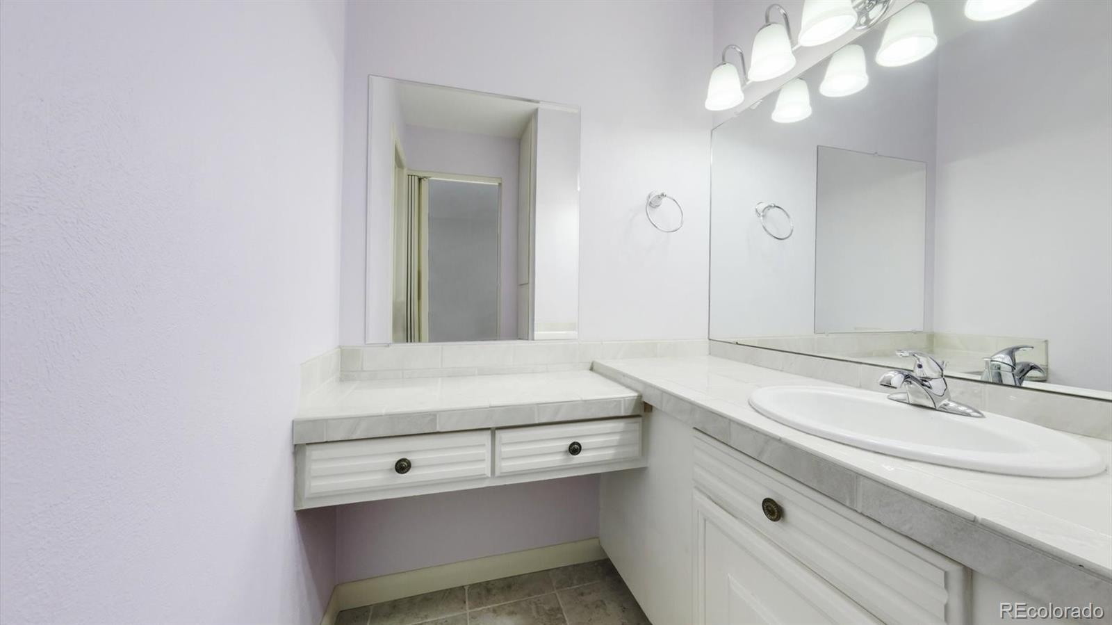 3292 South Oneida Way Denver, CO 80224 - Photo 27 of 44 a bathroom with a sink a mirror and a light fixture