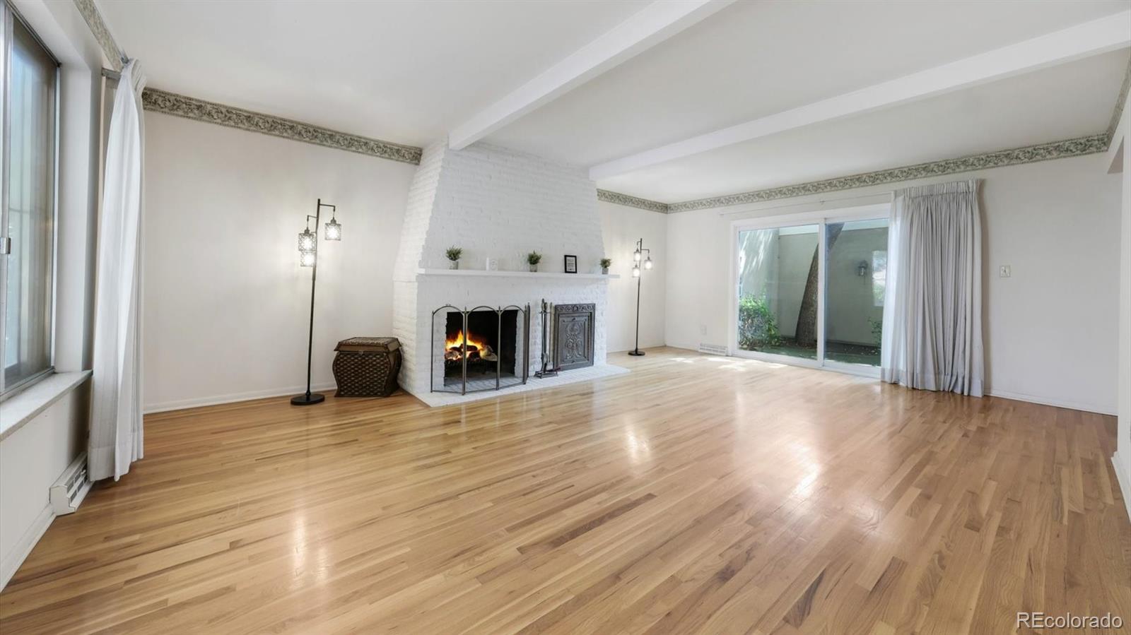 3292 South Oneida Way Denver, CO 80224 - Photo 6 of 44 an empty room with wooden floor fireplace and windows