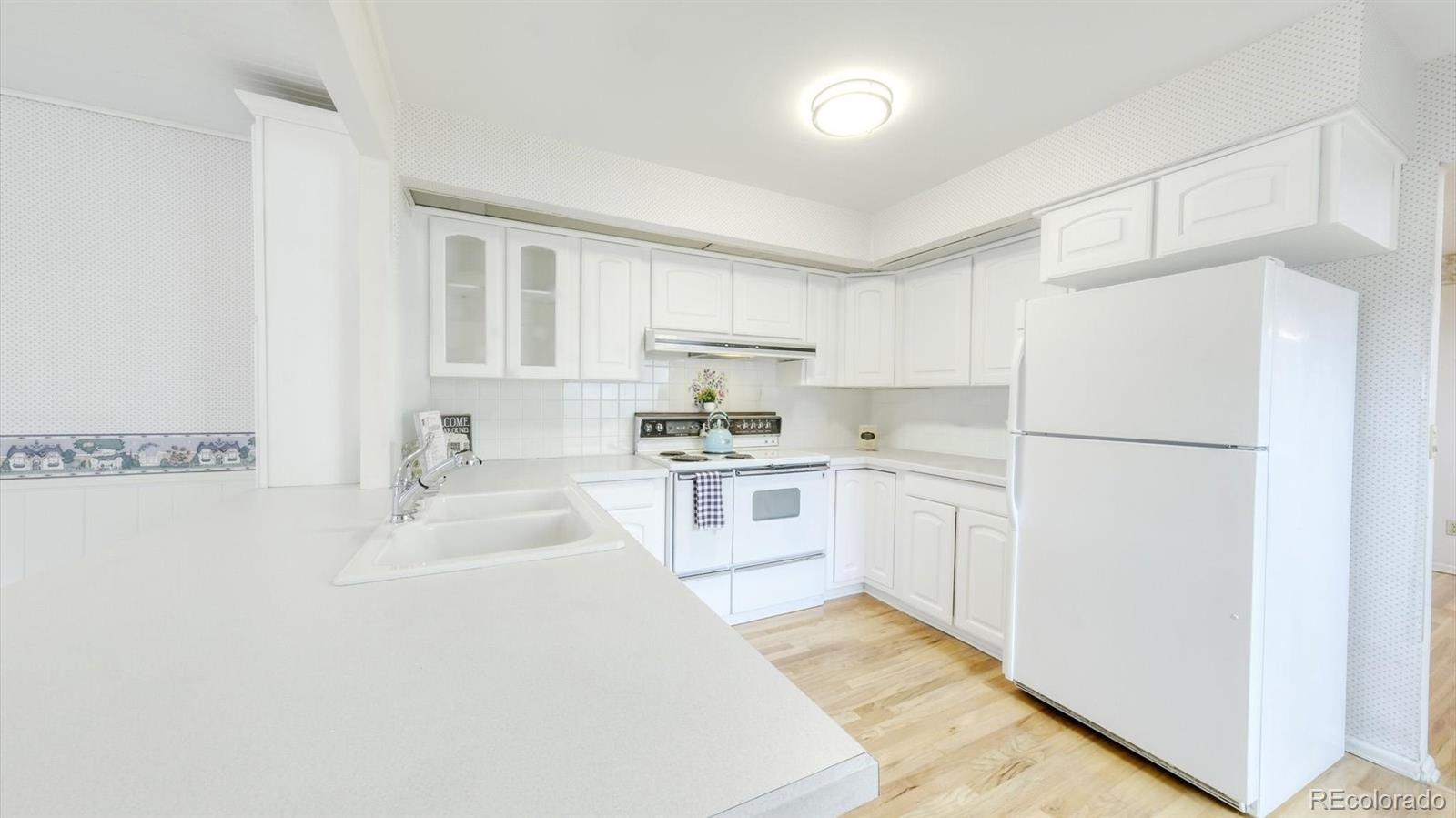 3292 South Oneida Way Denver, CO 80224 - Photo 7 of 44 a kitchen with white cabinets and white appliances