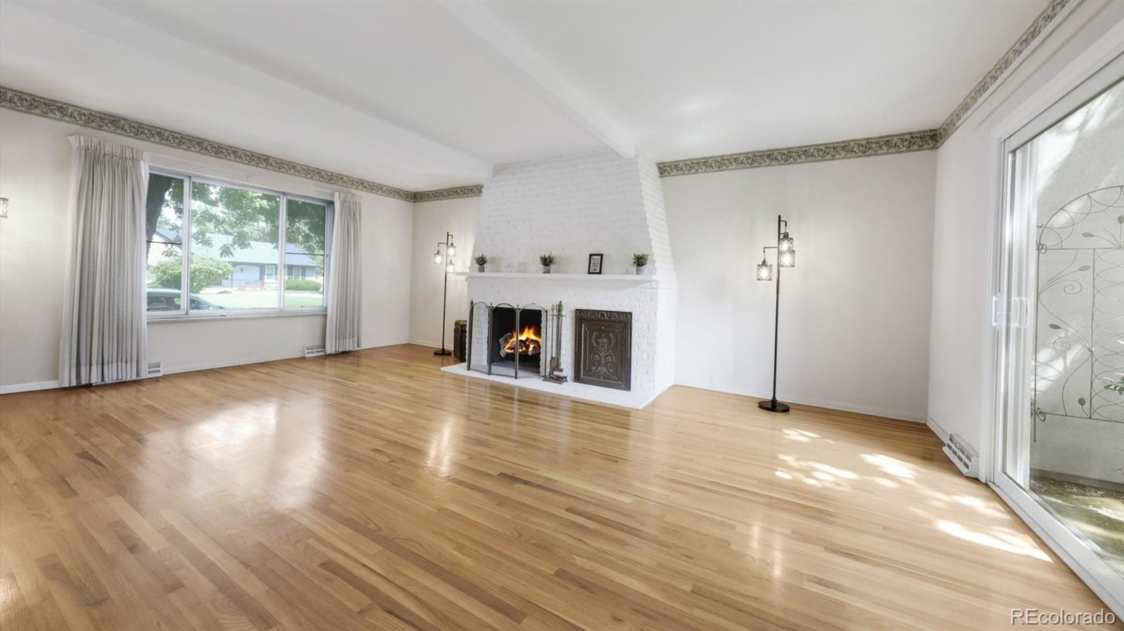 3292 South Oneida Way Denver, CO 80224 - Photo 10 of 44 a view of empty room with wooden floor and fireplace
